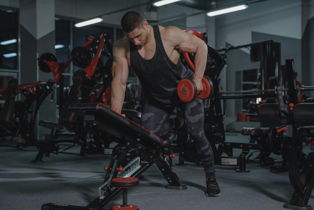 A strong, muscular man lifting dumbbells in a modern gym environment. muscle building